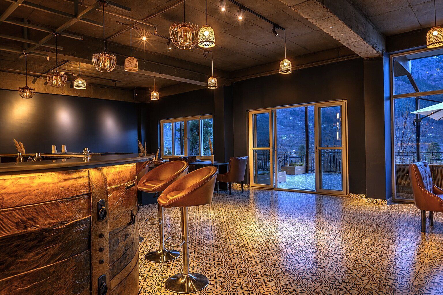 A bar area with wooden bar counter, leather bar stools, and hanging pendant lights.