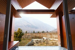 A wooden interior with a view of a mountainous landscape through an open doorway. - The Voyage Resort, Manali (Manali)