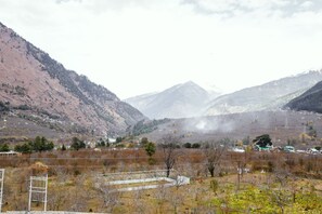 A mountainous landscape with a small settlement, including houses and a greenhouse. - The Voyage Resort, Manali (Manali)