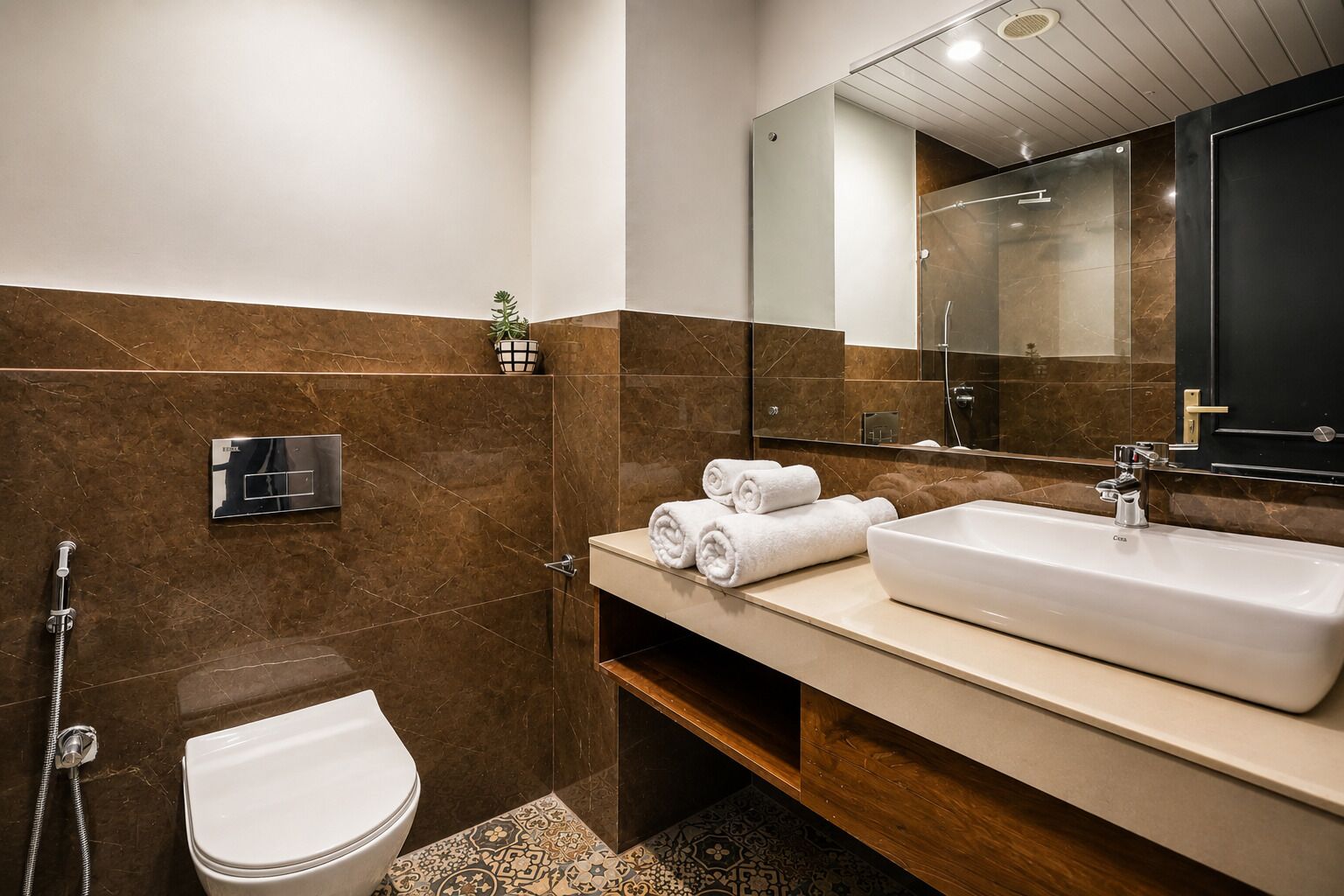 Un baño moderno con un espejo grande, un lavamanos y un inodoro.