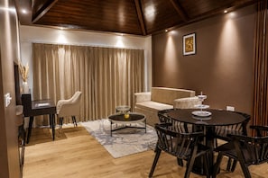 A modern living room with a sofa, a round dining table, and a coffee table. - The Voyage Resort, Manali (Manali)