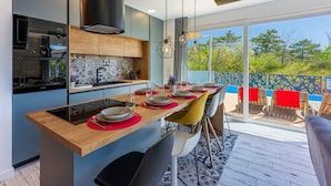 A modern kitchen with a central island, built-in appliances, and a large sliding glass door leading to an outdoor deck. - Villa with modern equipment and swimming pool (Crikvenica)