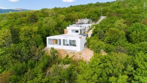 A modern, white building nestled in a lush, green forested area with a clear sky. - Holiday home with sea view, whirlpool and sauna (Crikvenica)