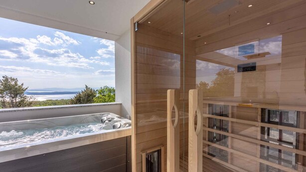 A modern bathroom with a glass shower enclosure, a bathtub with a view of the sea, and a wooden floor. - Holiday home with sea view, whirlpool and sauna (Crikvenica)