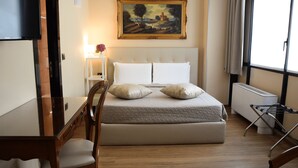 A bedroom with a bed, a desk, a chair, a painting, and a window. - Hotel Valentino Du Parc (Turin)