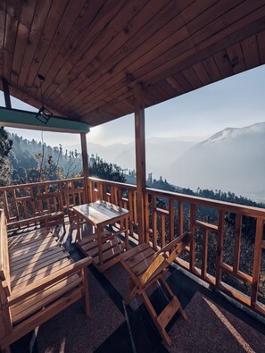 Enjoy breathtaking views of the surrounding mountains from this outdoor deck with a table and chairs.