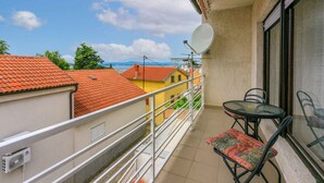 Ein Balkon mit Tisch und Stühlen, einer Satellitenschüssel und Blick auf benachbarte Gebäude.