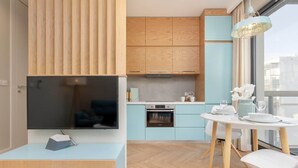 Una cocina moderna con armarios azul claro, encimera de madera y comedor con mesa y sillas blancas.