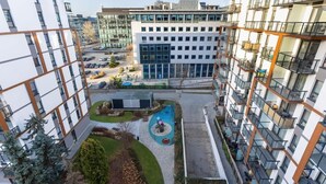 Un edificio residencial de varios pisos con balcones, un patio central y un área de estacionamiento.