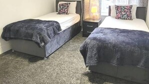 Habitación de hotel con dos camas, una mesita de noche, una lámpara y un cuadro en la pared.