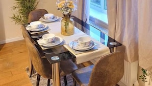 Een eetruimte met een tafel voor vier personen, een spiegel aan de muur en een uitzicht op het buitenlandschap door grote ramen.
