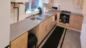 Een kleine keuken met een inbouwfornuis, een spoelbak en een raam.