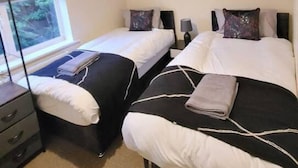 Hotelkamer met twee bedden, een groot raam, een bloemschilderij en een bureau met een lamp.