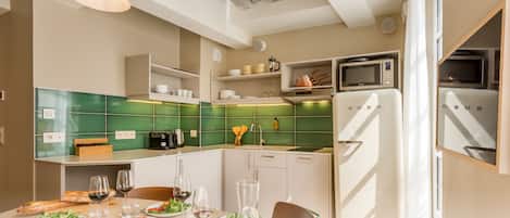 A modern kitchen with white appliances, green tiles, and a dining area set for a meal.