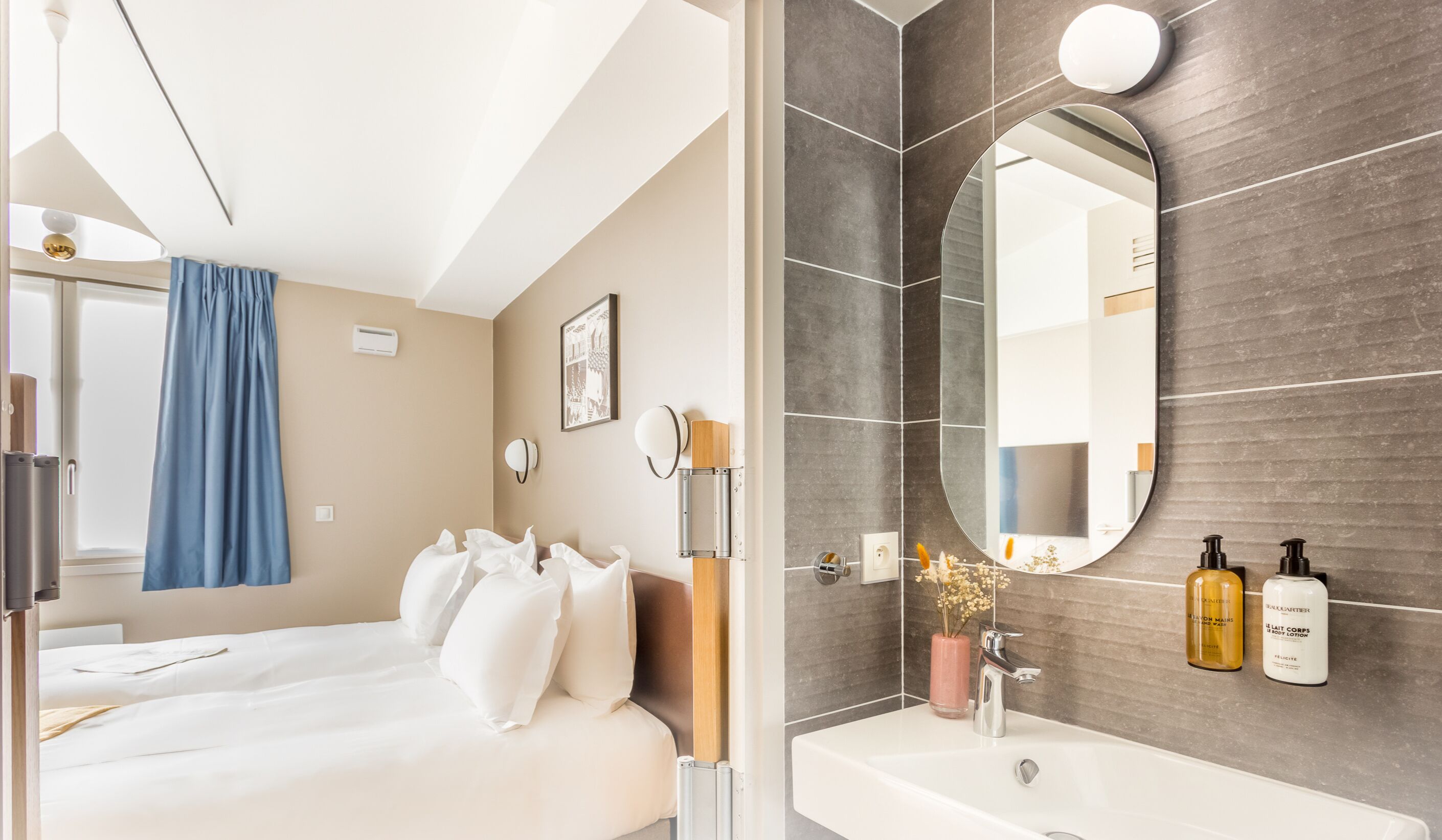 Ein modernes Hotelzimmer mit einem Bett, einem Badezimmer mit einem großen Spiegel und Toilettenartikeln am Waschbecken.