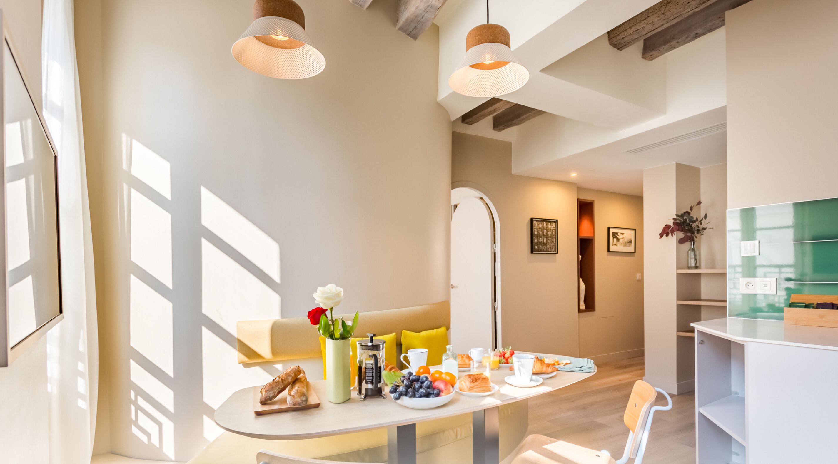 A modern kitchen with a breakfast setup, including a coffee machine, fruits, and pastries.