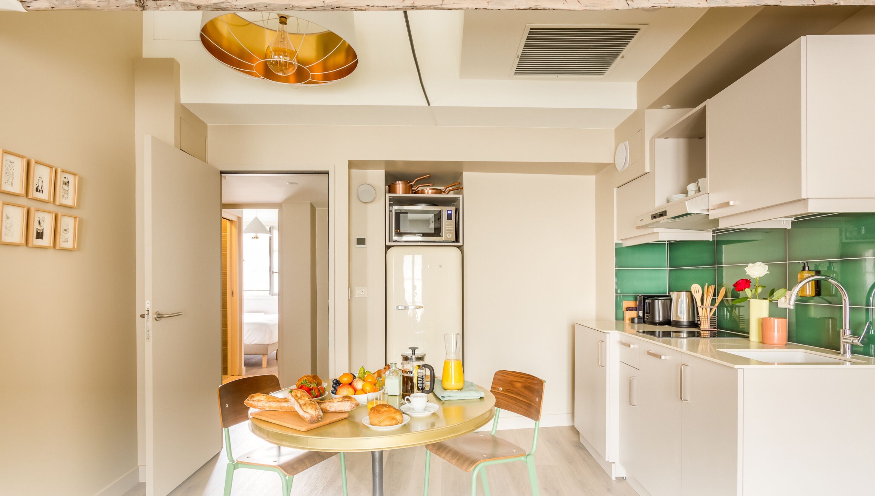 Cucina moderna con forno a microonde, forno e schienale verde. È presente un tavolo da pranzo con stoviglie per la colazione e sedie.