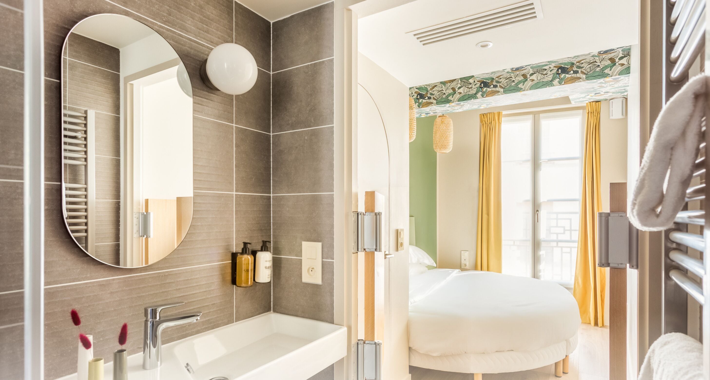 A modern bathroom with a large mirror, a white sink, and a towel rack.