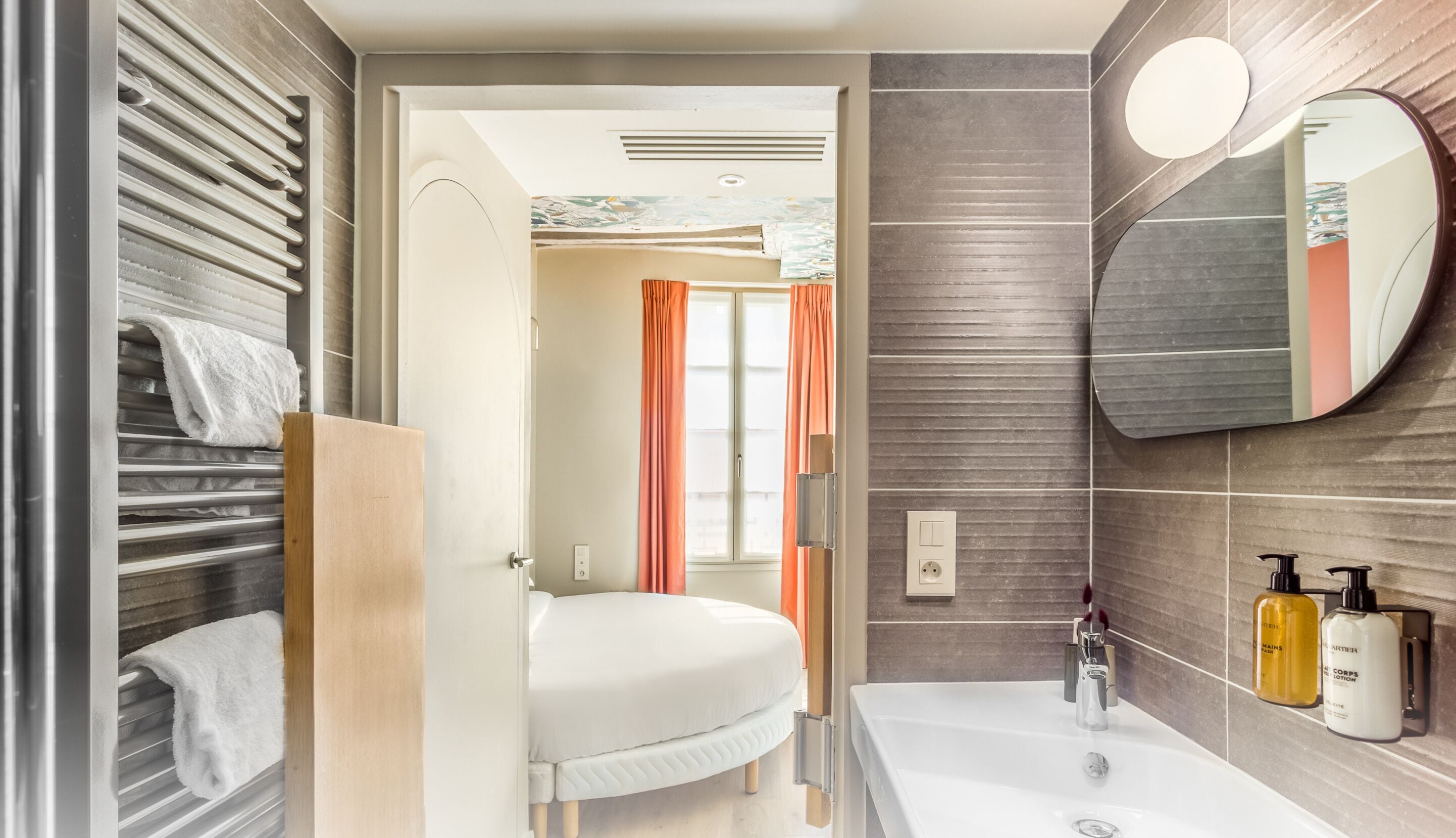 A modern bathroom with a white sink, mirror, and towel rack.