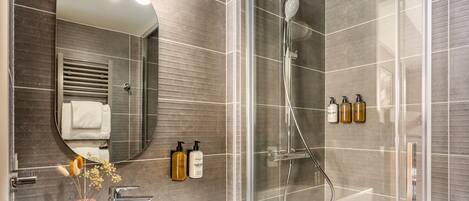 A modern bathroom with a glass-enclosed shower, a white sink, and a large mirror.