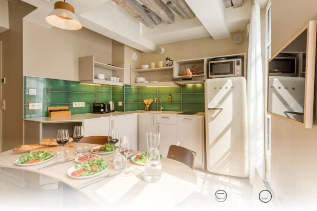A modern kitchen with green tiles, white cabinets, and a white refrigerator.