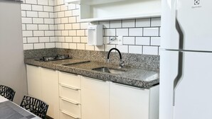 Een moderne keuken met witte kastjes, een granieten aanrechtblad, een ingebouwde magnetron en een koelkast.