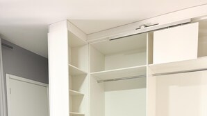 Een inloopkast met meerdere planken en hangruimte, een deur en een houten vloer.
