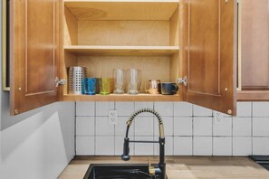 A kitchen with a wooden cabinet, a stainless steel sink, and a tiled backsplash. - W Oxford St Charm | 1 BR Apartment |Central Philly (Philadelphia)