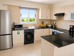 A modern kitchen with a stainless steel refrigerator, a microwave, a washing machine, and a toaster.