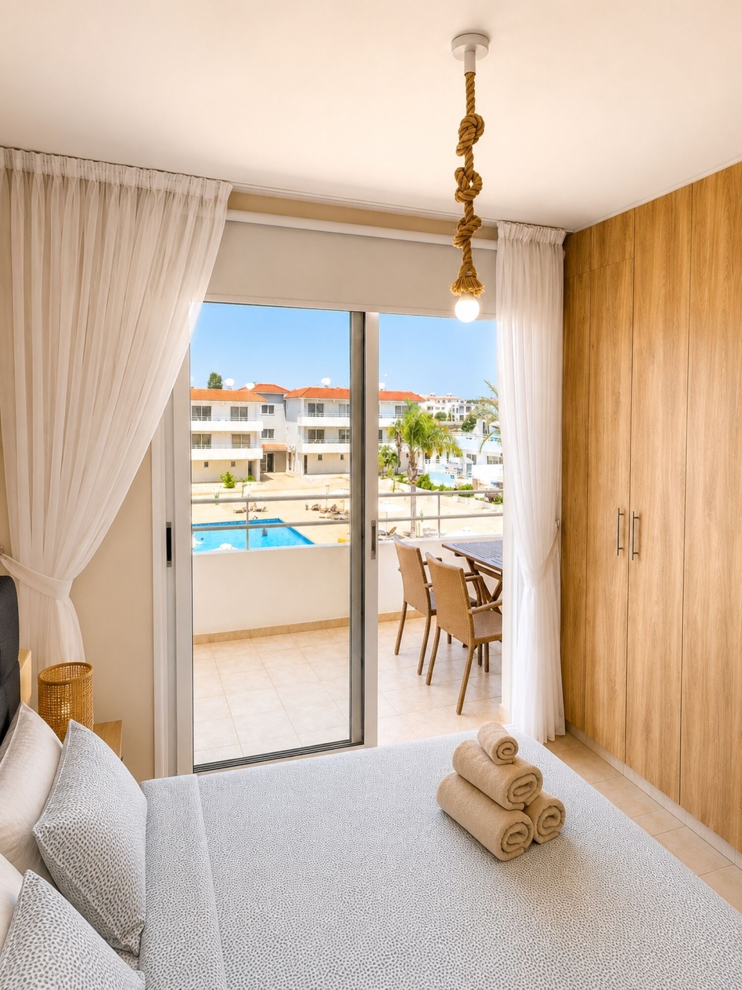 Une chambre d’hôtel avec un lit, une vue sur la piscine et un coin repas.