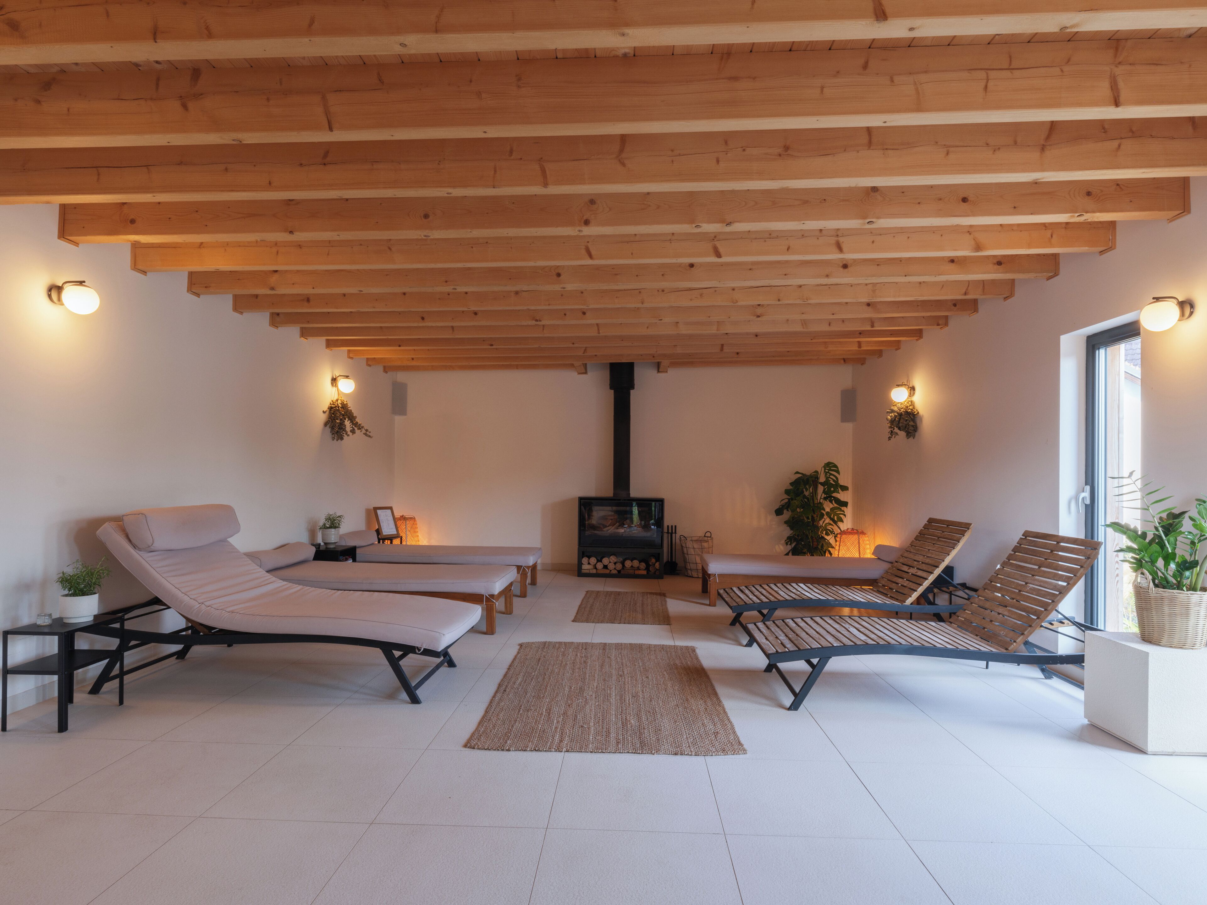 A spacious room with wooden beams, a fireplace, and multiple lounge chairs.