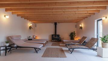 A spacious room with wooden beams, a fireplace, and multiple lounge chairs.