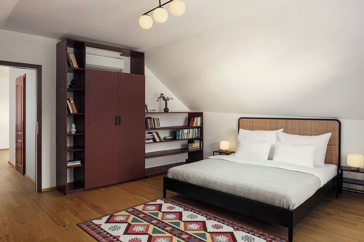 A bedroom with a bed, a bookshelf, a desk, and a nightstand.