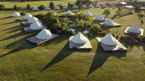 A series of white tents arranged in a field with a view of distant hills. - po.spolu wellness resort (Mokrovraty)