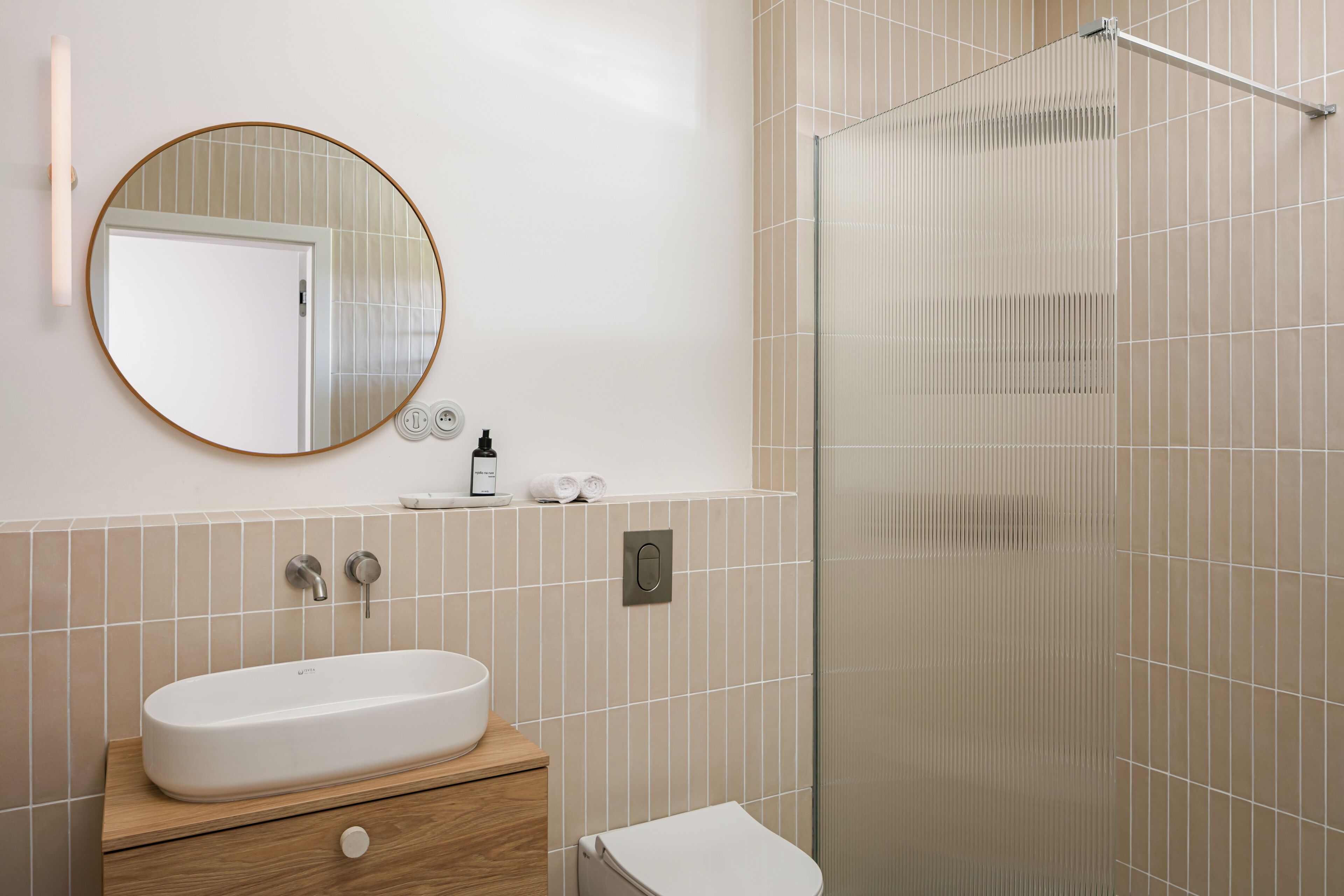 Ein modernes Badezimmer mit rundem Spiegel, Waschbecken und Duschkabine.