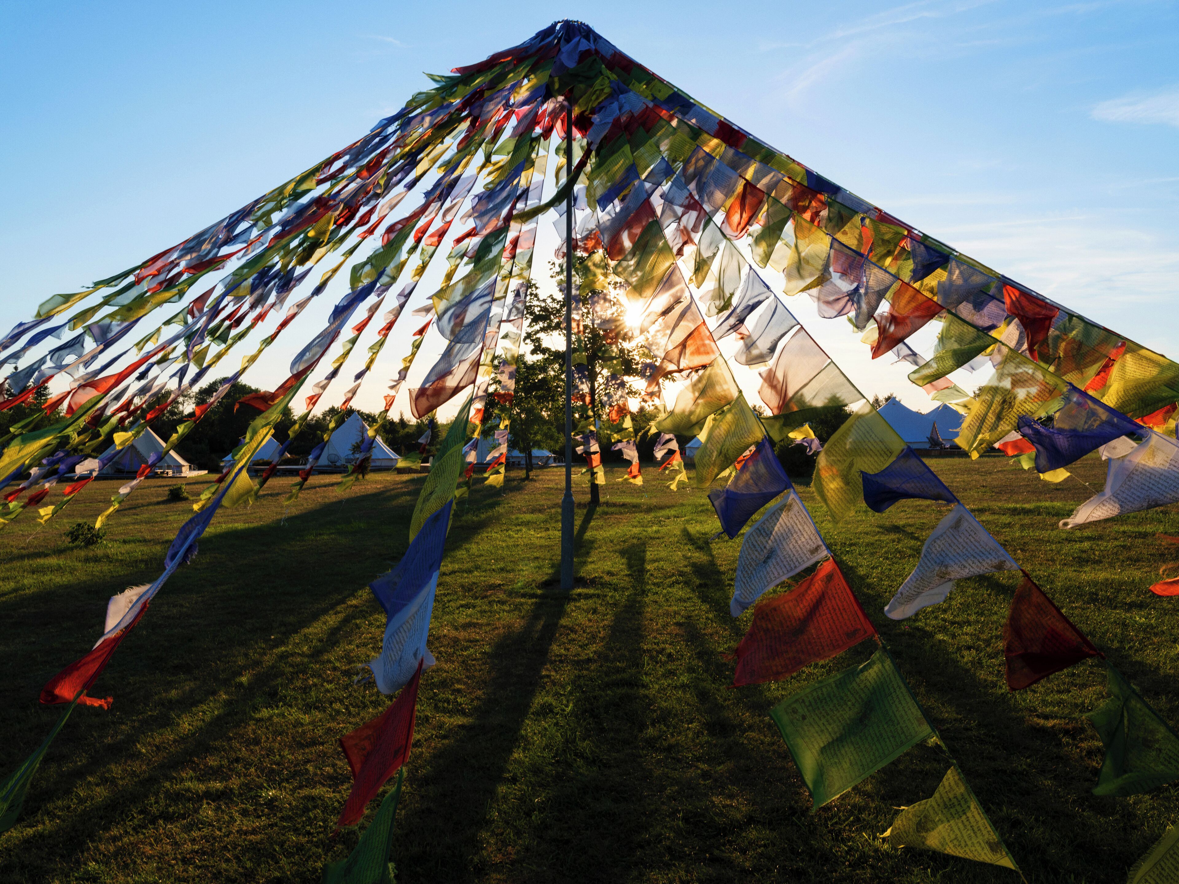 Une grande installation de drapeaux de prières aux couleurs vives, installée dans un champ d’herbe.