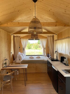 A cozy cabin interior with a bed, kitchenette, and dining area. - po.spolu wellness resort (Mokrovraty)