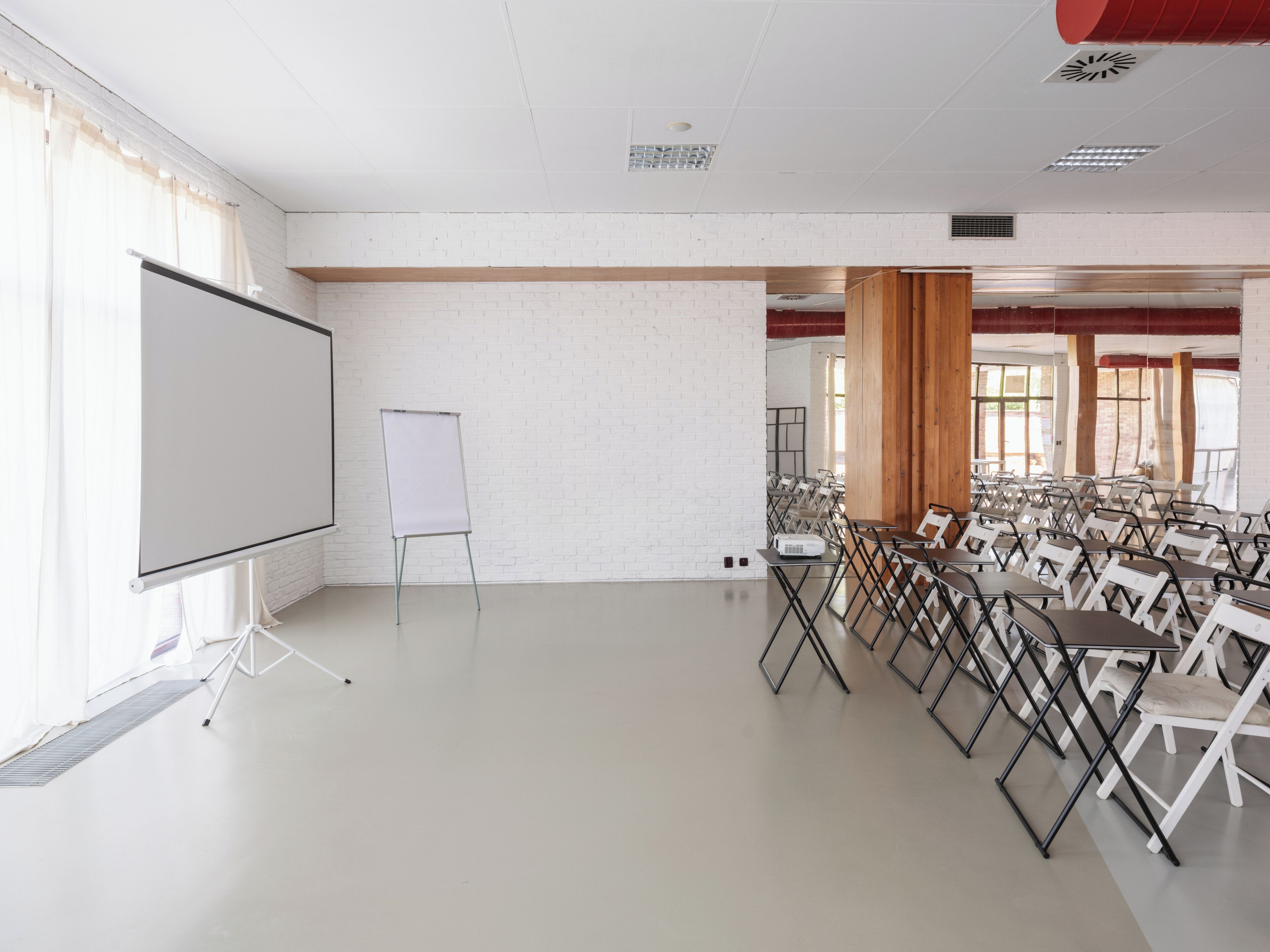 A conference room with a whiteboard, folding chairs, and a brick wall.