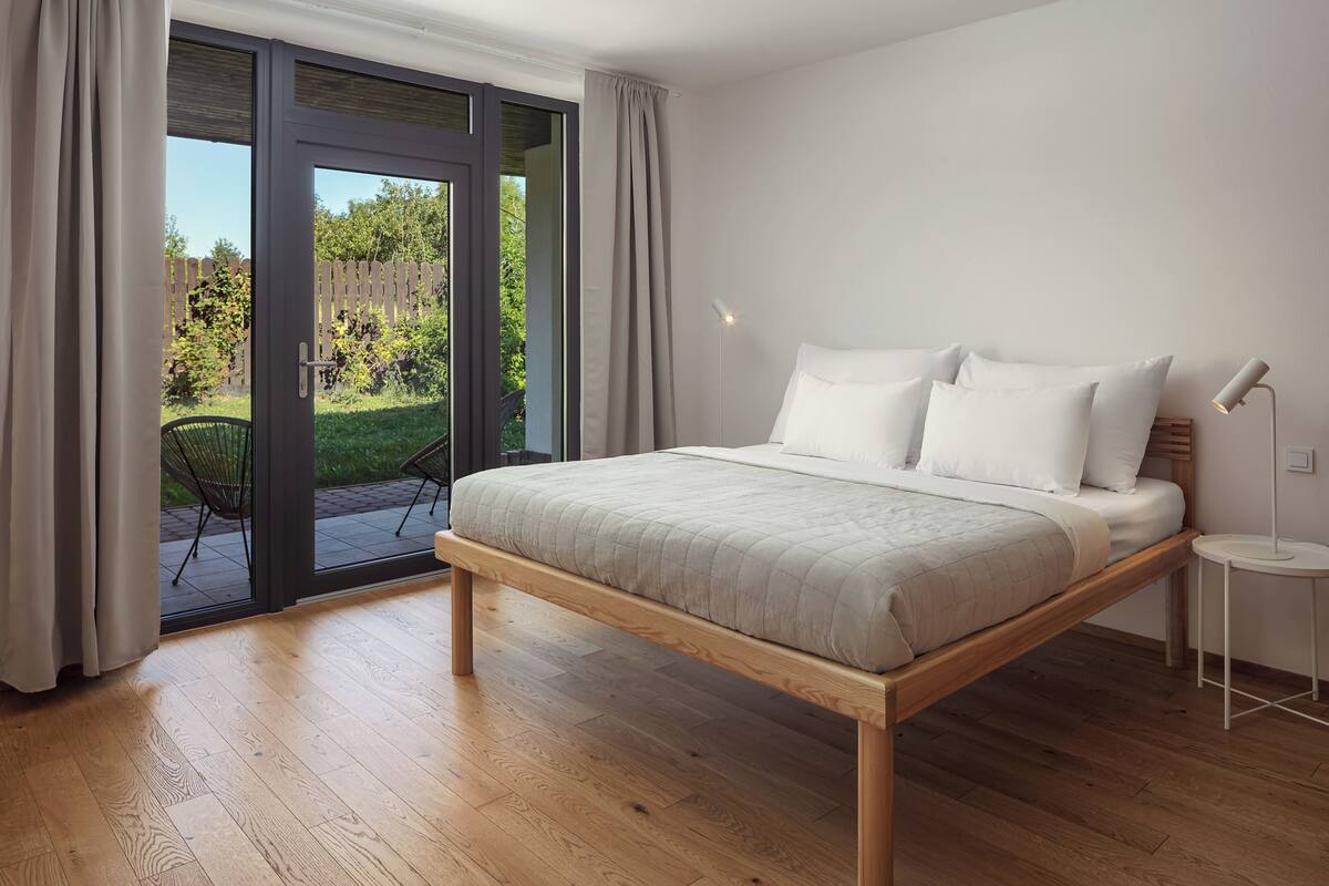 A bedroom with a bed, a chair, and a view through a glass door.