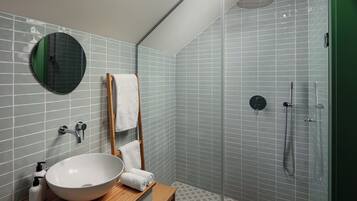 Un baño con un espejo redondo, un lavabo, un perchero para toallas y una ducha.