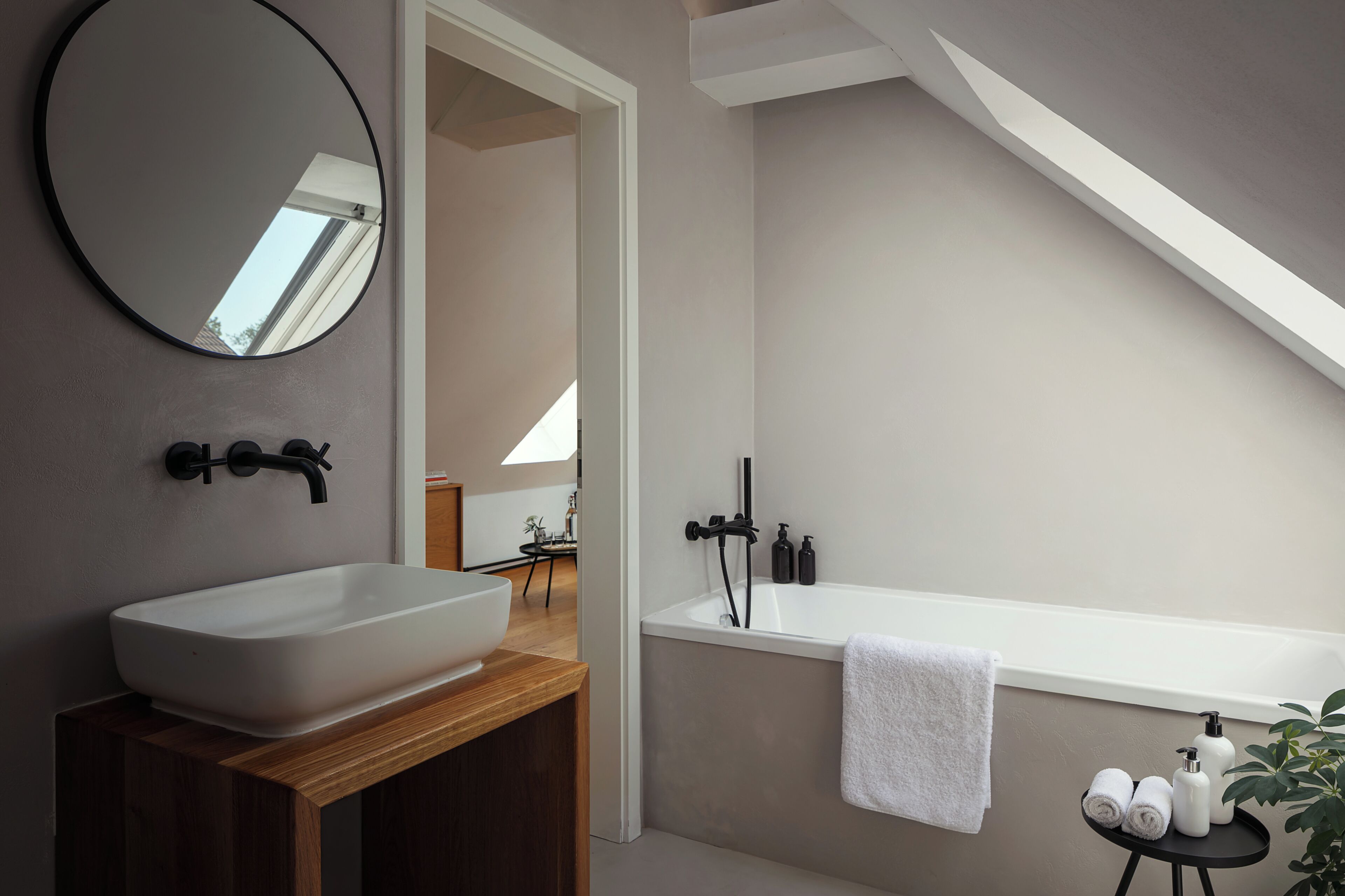 A modern bathroom with a freestanding sink, a bathtub, and a mirror.