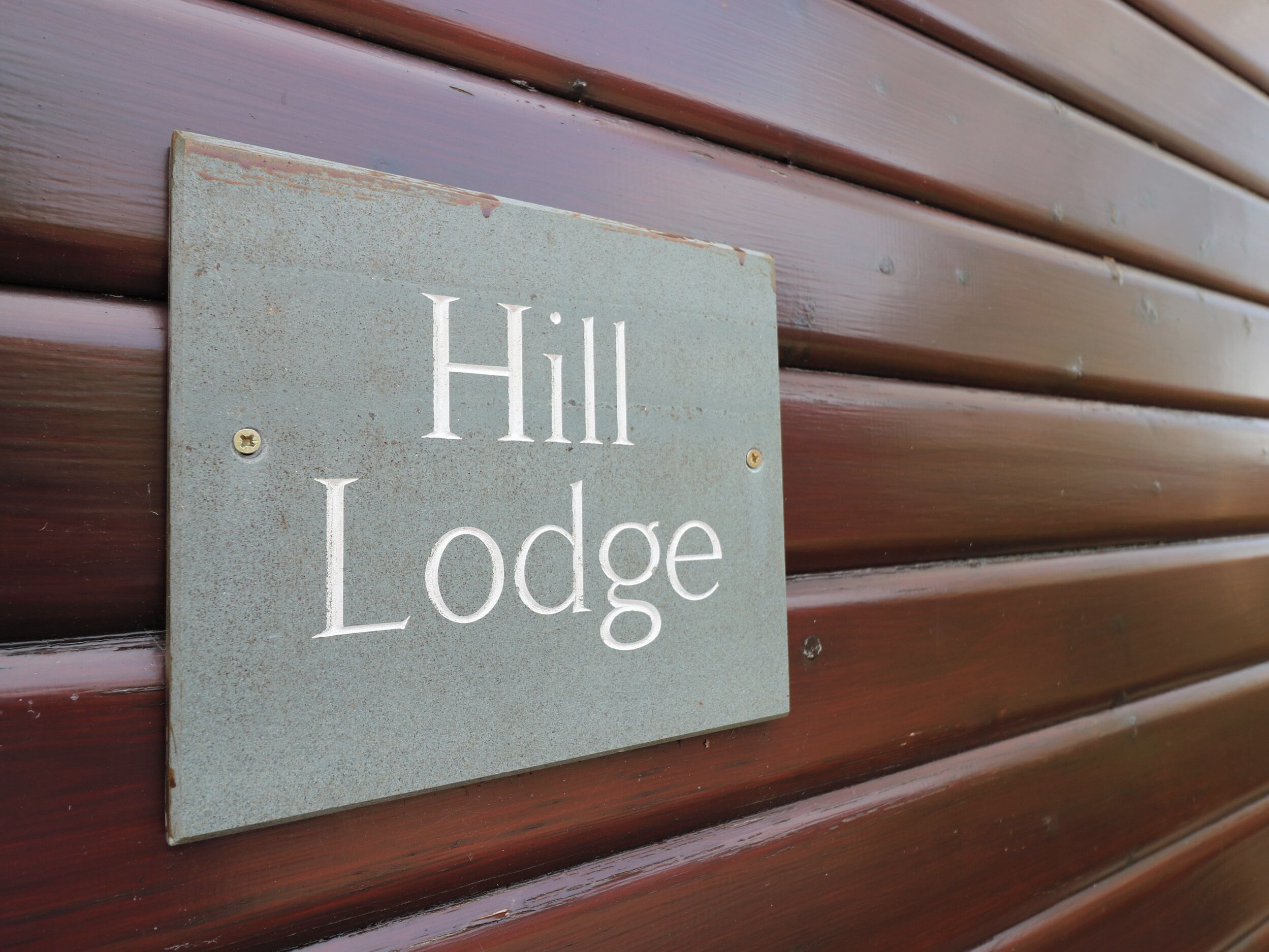 Et skilt på en trævæg med teksten "Hill Lodge".