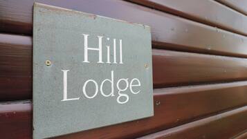 Et skilt på en trævæg med teksten "Hill Lodge".