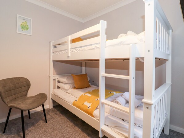 Une chambre avec un lit superposé, une chaise et une carte encadrée accrochée au mur.