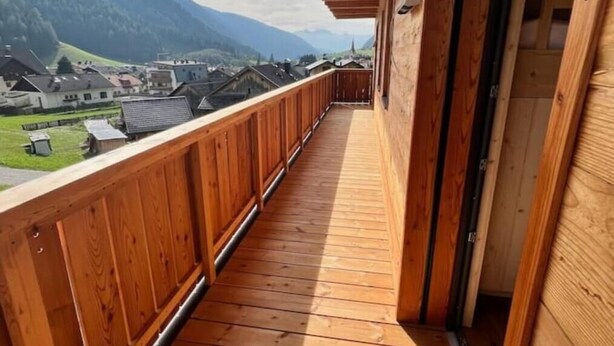 Ein Holzbalkon mit Blick auf ein Dorf und Berge.