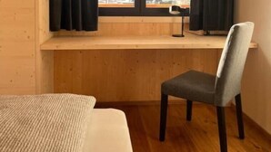Ein Zimmer mit einem Holztisch, einem Stuhl und einem Bett.