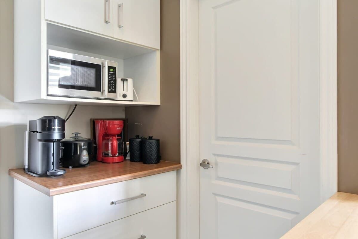 Een kitchenette met een magnetron, koffiezetapparaat en broodrooster.