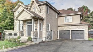 A two-story house with a stone facade, a front porch, and a garage with two doors. - L'Artiste | Chic condo à Québec by Alchalet (Quebec)