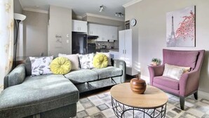 A living room with a grey sectional sofa, a round coffee table, and a pink armchair. - L'Artiste | Chic condo à Québec by Alchalet (Quebec)