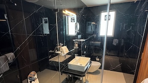 Uma casa de banho moderna com cabine de duche em vidro, lavatório e sanita.